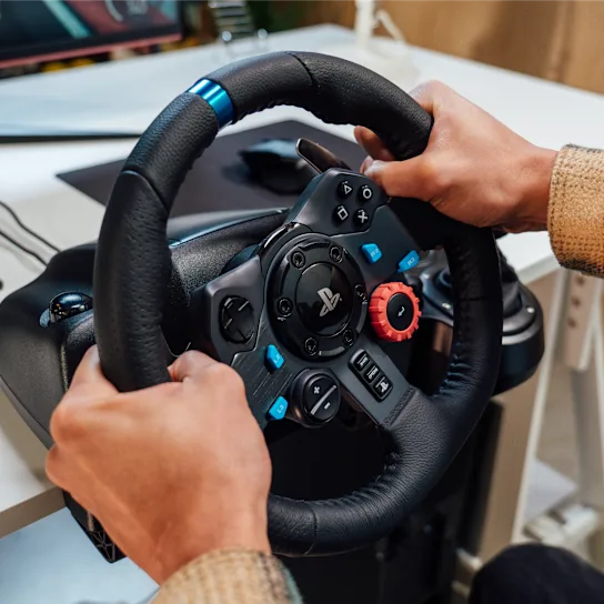 Hráč drží volant Logitech G29 připevněný ke stolu